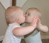 Un nadó es fa una petó al mirall